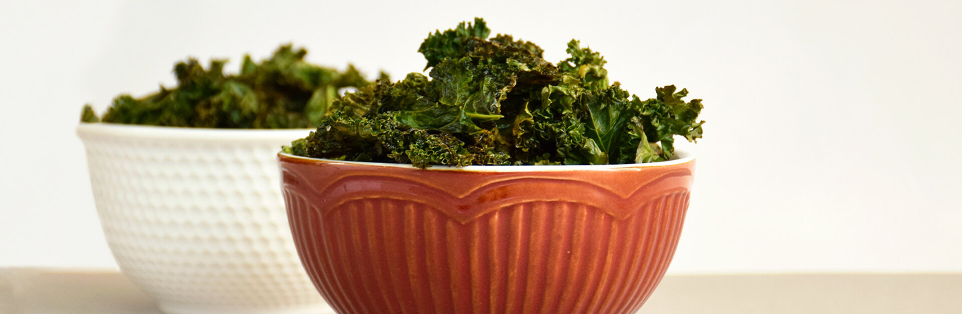 Two bowls of baked kale chips.